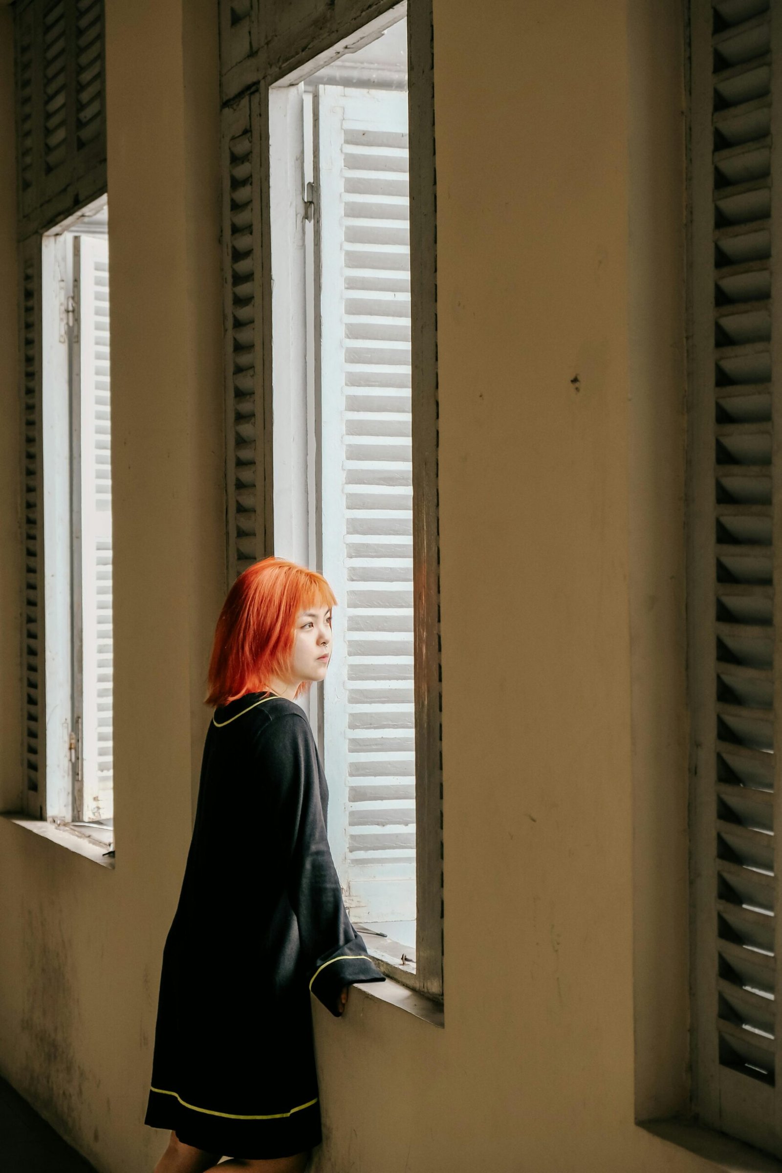 Pessoa adulta sentada em ambiente iluminado por luz natural, em momento de introspecção, cenário representando a experiência de dor crônica com componente emocional.