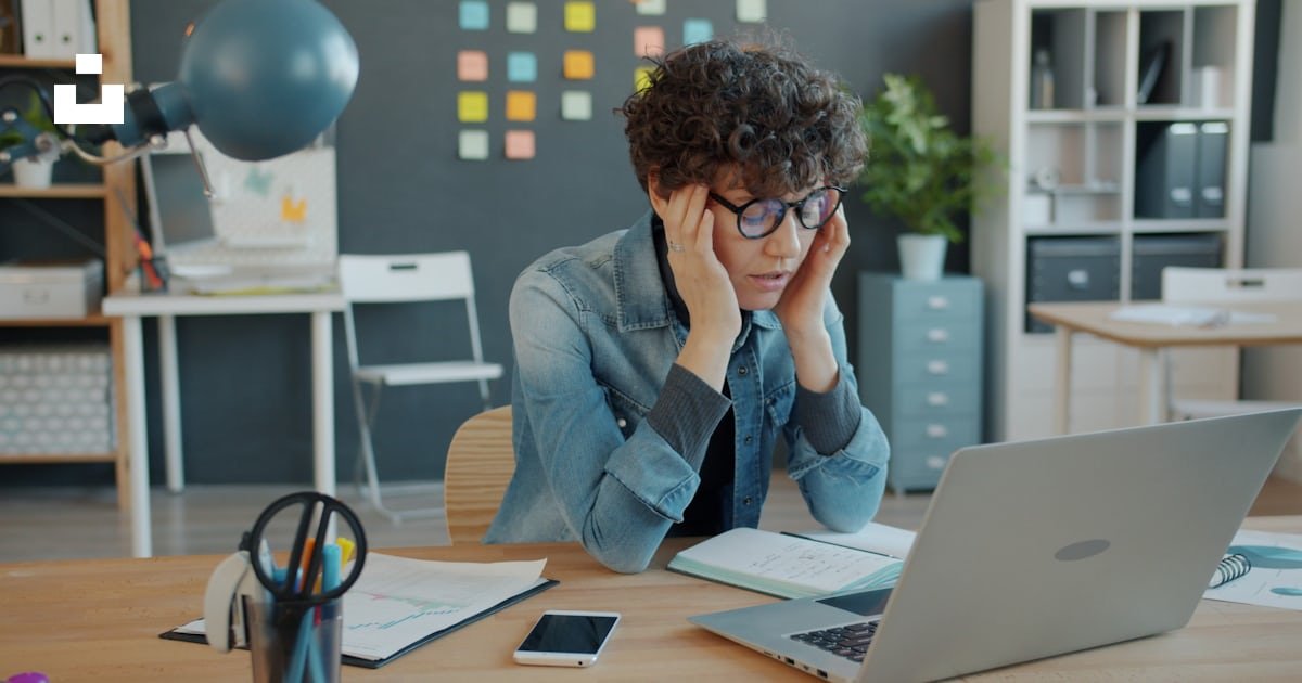 Pessoa adulta em home office com a mão apoiada na região cervical, indicando desconforto após horas de trabalho em casa — cenário típico de dor nas costas por postura sustentada.